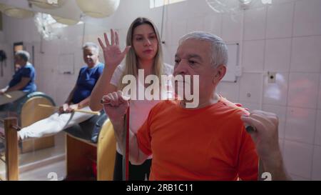 Happy senior exercising with Pilates Machine being coached by female instructor. Older person taking care of body health at old age workout routine Stock Photo