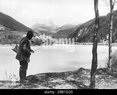 1930s TWO MEN WITH FISHING GEAR RODS CREEL WADERS TACKLE BOX HAVING PICNIC  LUNCH COFFEE FROM THERMOS - SuperStock