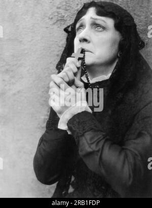 Hollywood, Califoria:  c. 1923 A worried looking woman holding her rosary to her lips. Stock Photo