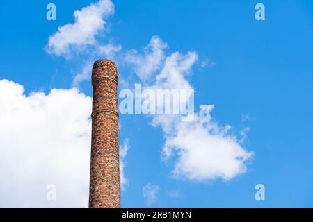 Old ruined brick chimney in front of cloudy blue sky Stock Photo