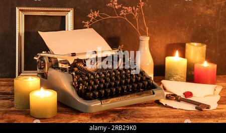Vintage typewriter, burning candles, old key and envelope on wooden table Stock Photo