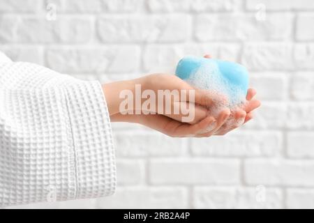 Hands with soap on white brick background Stock Photo