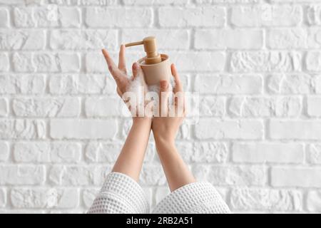 Hands with liquid soap on white brick background Stock Photo