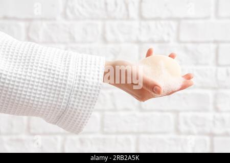 Hand with soap on white brick background Stock Photo