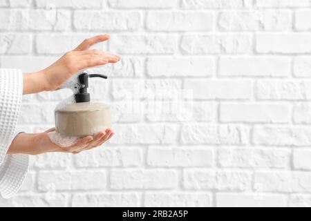 Hands with liquid soap on white brick background Stock Photo