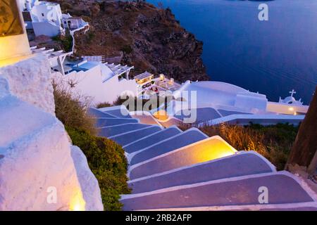 view down from steep narrow gray-white painted stairs leading to picturesque carved cave houses turned to upscale resort hotels on the edge Stock Photo