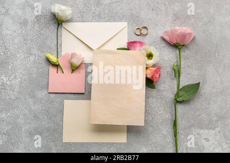 Composition with envelopes, blank cards, wedding rings and eustoma flowers on grey background Stock Photo