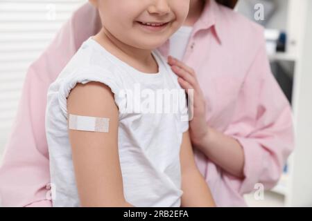 Children's hepatitis vaccination. Mother and her daughter with medical plaster in clinic, closeup Stock Photo