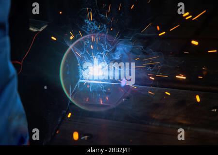 Using semi-automatic argon arc welding skilled welder executes precise during welding works. Stock Photo