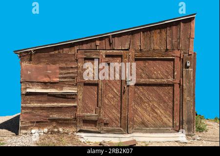Closeup of isolated barn or shack with weathered wood shows patches, covers & frames. Extra wood frames added. Slanted roof is unusual. Stock Photo