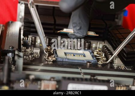 Technician assembling desktop computer with plug in CPU to motherboard socket Stock Photo