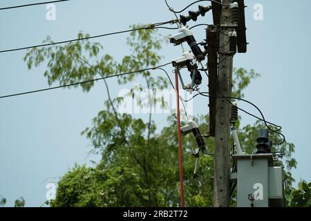 electrician using a clamp stick to repair dropping fuse cutout on insulator supported high-voltage electric power pole. Stock Photo