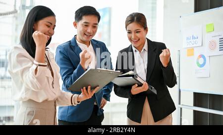 Group of cheerful and successful millennial Asian businesspeople are celebrating their project success in the room together. Stock Photo