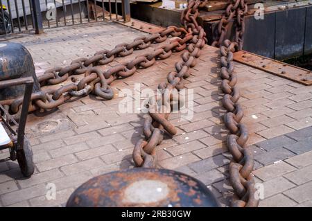 heavy rusty iron chains are placed around a bollard Stock Photo
