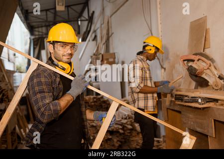 Happy worker working together in wood furniture factory, staff employee male making wooden wardrobe. Stock Photo