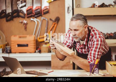 Senior professional male caucasian diy wood working making home furniture in workshop, home renovate. Stock Photo