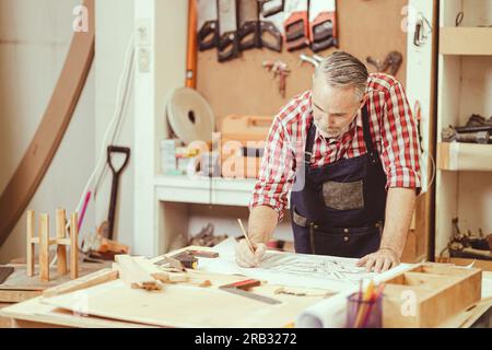Senior professional engineer architect male working design drawing floor plan home furniture and renovate in workshop. Stock Photo