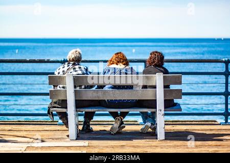 Three older women sitting on a bench together Stock Photo