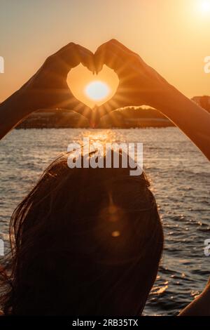 Silhouette against the sunset - hands folded in the shape of a heart ...