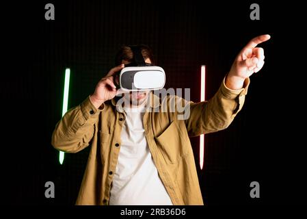 Virtual reality glass vr. Young man in digital glasses for 3d virtual reality game on dark background. Augmented reality, game, future technology Stock Photo