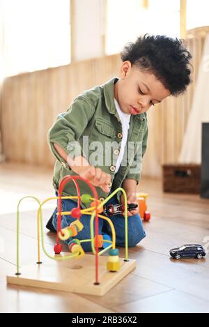 Concentrated latinos boy playing toys sitting on warm floor in modern living room. Baby development. Small tower. Learning creative concept Stock Photo