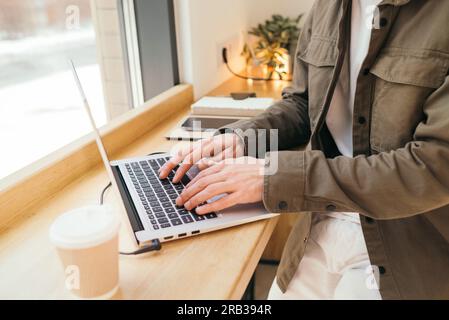 A caucasian man write in notepad on a cafe. work process. A man with a beard in a shirt is sitting in a cafe with a laptop, remote work, freelance Stock Photo
