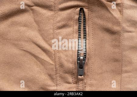 zipper on brown fabric as background close-up Stock Photo