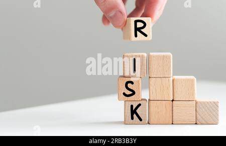 Man removes blocks with the word Risk. The concept of reducing possible risks. Insurance, stability support. Legal protection of business interests Stock Photo