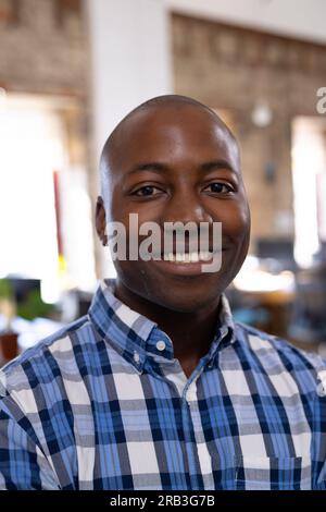 Portrait of happy african american casual businessman wearing checked shirt in office. Business, confidence and work, unaltered. Stock Photo