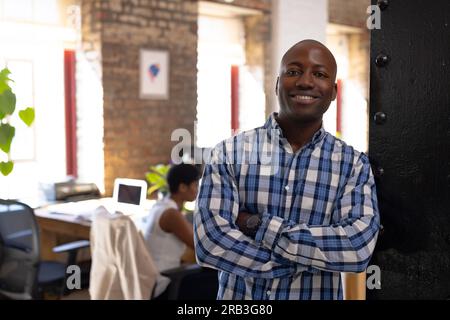 Portrait of happy african american colleagues with arms crossed in creative office. Business, work and teamwork, unaltered. Stock Photo