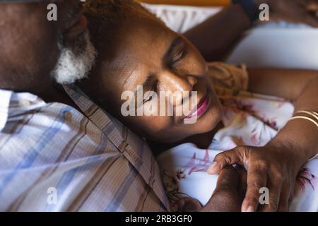 Senior african american couple lying on sofa and embracing at home. Senior lifestyle, relaxing and retirement, unaltered. Stock Photo
