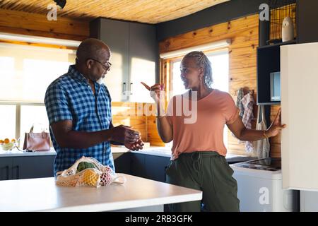 Happy senior african american couple unpacking groceries in kitchen. Senior lifestyle, relaxing, food, cooking and retirement, unaltered. Stock Photo