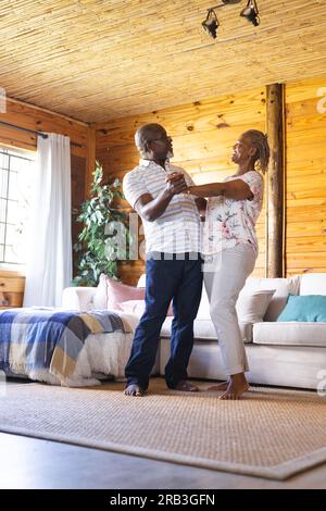 African American couple dancing in sunlit room at home, smiling at each ...