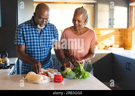 Happy senior african american couple unpacking groceries in kitchen. Senior lifestyle, relaxing, food, cooking and retirement, unaltered. Stock Photo