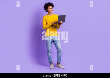 Full body size length cadre of cheerful optimistic man studying remote hold netbook learning maths isolated on violet color background Stock Photo