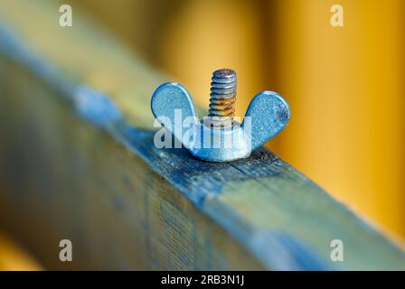 Close-up of screw and wing nut when repairing outdoor furniture. Stock Photo