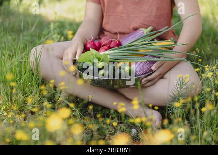 teen girl with vegetables picked in the summer garden behind the house Stock Photo