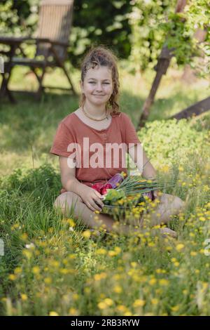 teen girl with vegetables picked in the summer garden behind the house Stock Photo