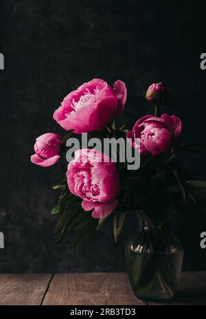 Still life of a bouquet of pink peony flowers in vase on table. Stock Photo