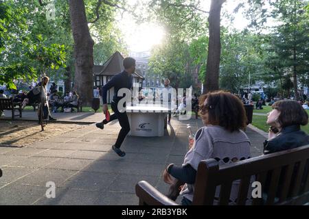 UK weather, 6 July 2023, London: After a few colder than average days, warm weather returns to London, bringing crowds into Soho. In Soho Square people enjoy the sunny evening chatting with friends or playing table tennis. Credit: Anna Watson/Alamy Live News Stock Photo