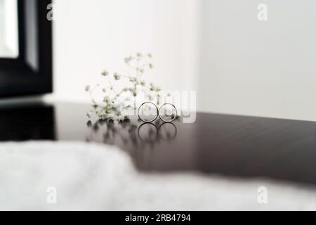 Hochzeitsringe auf einem braunen Holztisch mit einer Blumendekoration Stock Photo