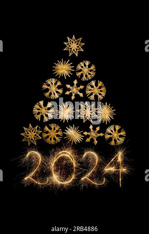 Christmas tree triangle made with straw snowflakes and 2024 new year written with sparkers isolated on black background Stock Photo