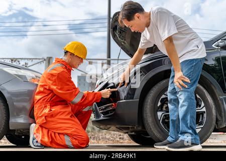 A man pointing out the scratches on his car from the car accident to the car insurance mechanic wearing yellow hardhat and orange jumpsuit or agent at Stock Photo