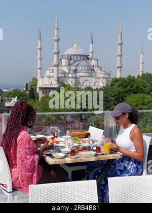 Two people dine at the  Seven Hills Restaurant terrace with the Sultan Ahmed Mosque aka Blue Mosque behind, Sultanahmet, Istanbul, Turkey. Stock Photo