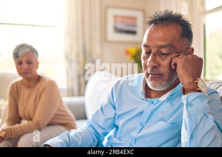 Couple arguing, stress and divorce with a senior man on a sofa in the living room of his home after a fight. Sad, anxiety or depression with an Stock Photo