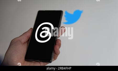 July 7th 2023, a hand holding a phone, the logo of Threads on the screen. On the background the blurry logo of Twitter. Stock Photo