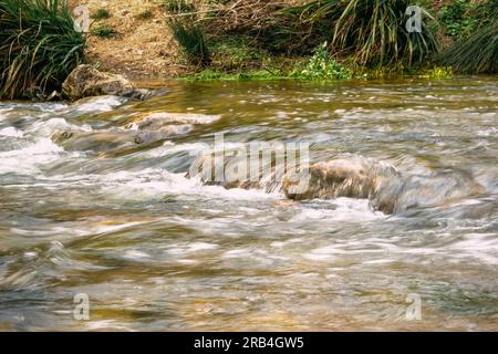 Rapid and powerful water flow between large rocks, close-up. Boulders in cold mountain river. Natural backgrounds Stock Photo