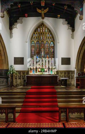 Skipton, North Yorkshire, England's Holy Trinity Church, as seen down its isle, complete with a red carpet and a spectacular stained glass window. Stock Photo