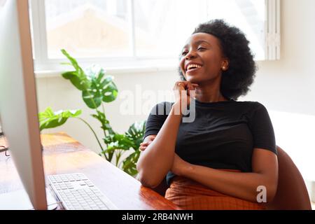 Beautiful Black woman working at desk in office, developer in tech start up Stock Photo