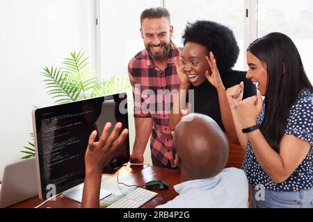 Development team celebrates successful app, coding review in office Stock Photo